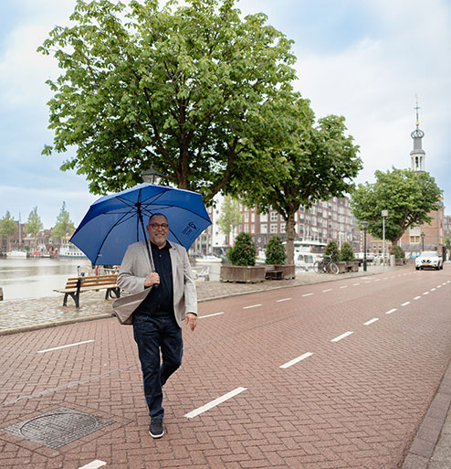Rob, makelaar in Castricum bij GoedVast Makelaars, loopt met een paraplu over straat